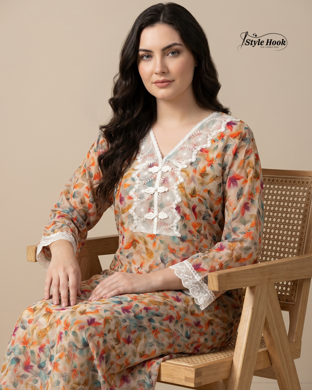 Woman wearing a floral dress sitting on a wooden chair with 'Style Hook' branding.